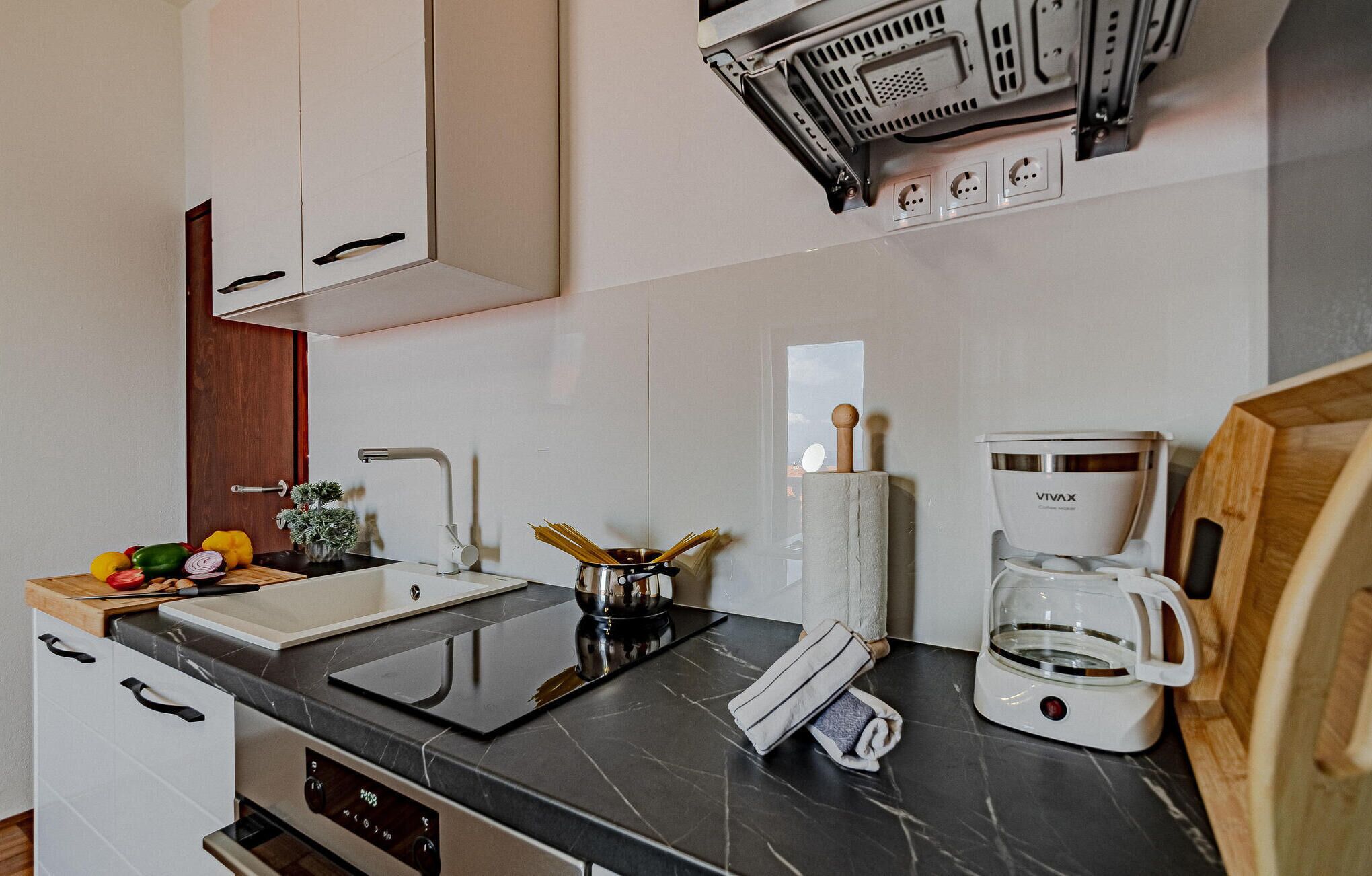 A modern kitchen with a built-in oven, a coffee maker, and a sink.