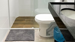 A modern bathroom with a glass shower enclosure, a white toilet, and a black sink with a marble countertop. - Hotel Lara 10 Curitiba (Curitiba)