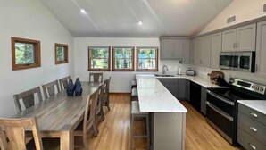 Una cocina moderna con una isla central, mesa de comedor de madera y armarios empotrados.