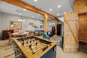 A room with a foosball table, a ping pong table, a sofa, and a coffee machine. - Sunset Chalet  Lakefront Hot Tub Game Room (Belgrade)