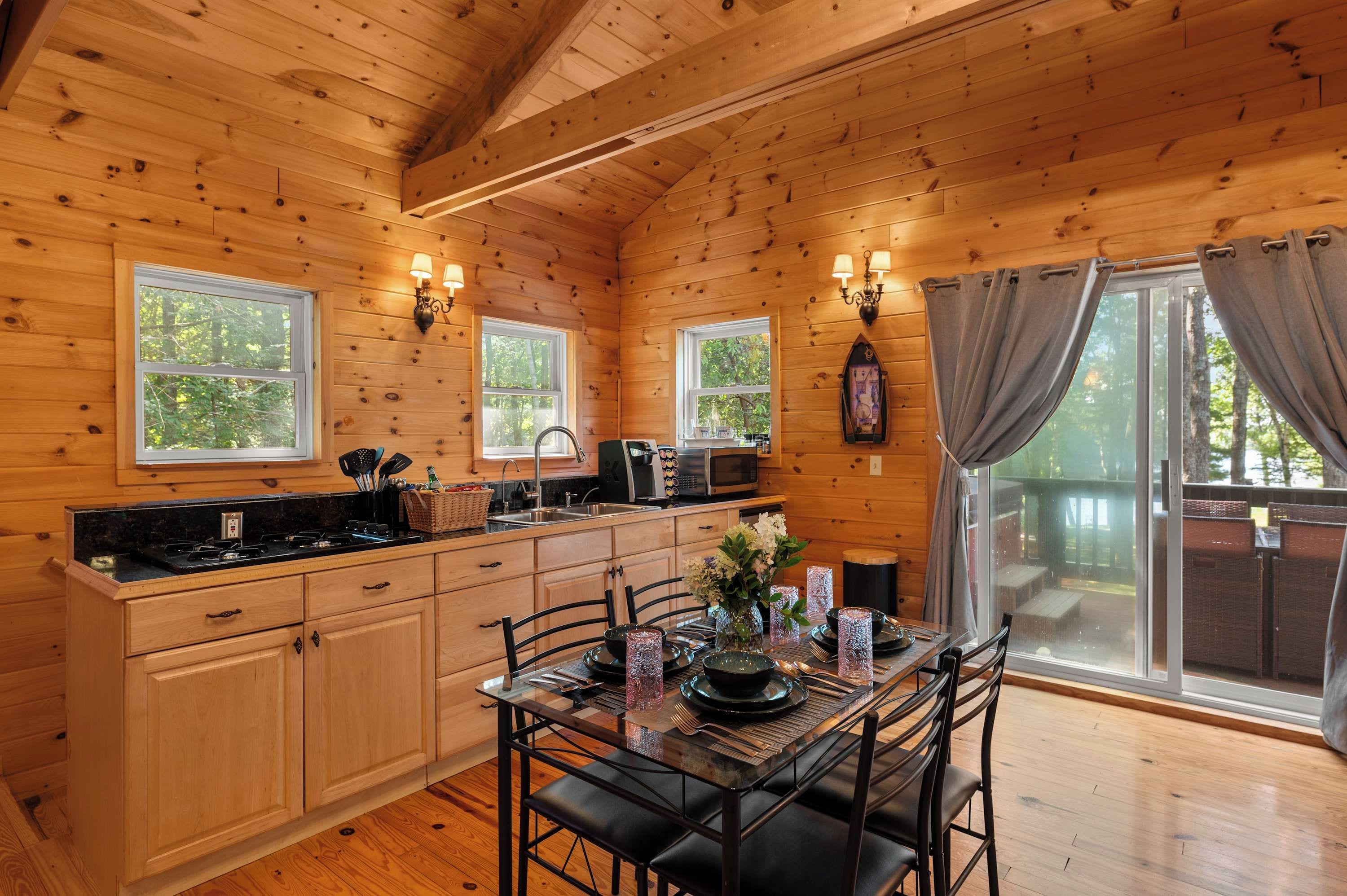 L’intérieur d’un chalet en bois comprend une cuisine, un coin repas et de grandes fenêtres.