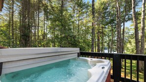 A hot tub on a deck with a forest view.