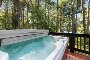 A hot tub on a deck with a view of a forest.