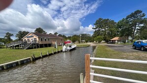 A narrow waterway with a dock, a boat, and a house with a deck. - Knot Three- Balcony View of ICW- Dog Friendly! (Coinjock)