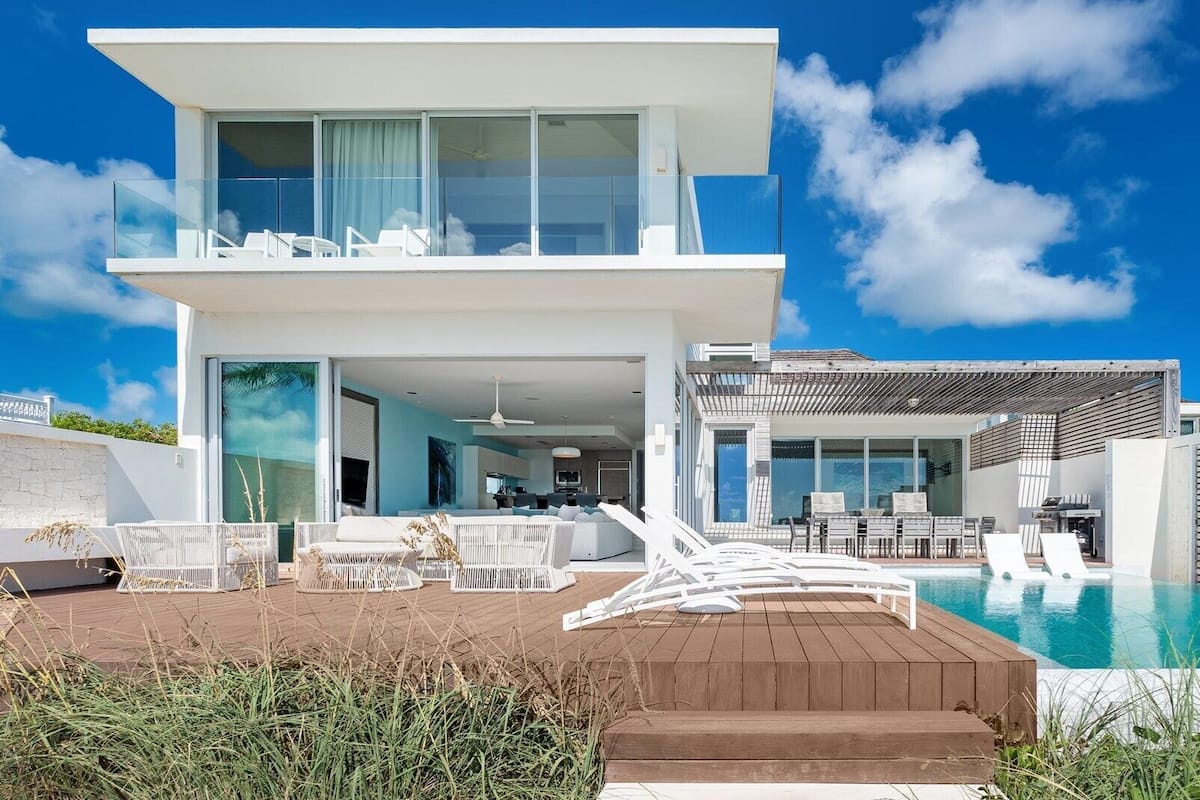 A modern two-story house with a swimming pool, outdoor seating, and a large balcony.