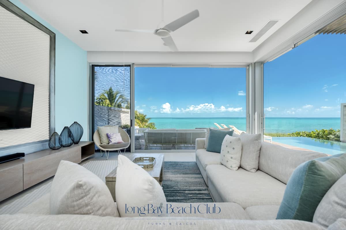 A spacious living room with a large TV, comfortable seating, and a view of the ocean.