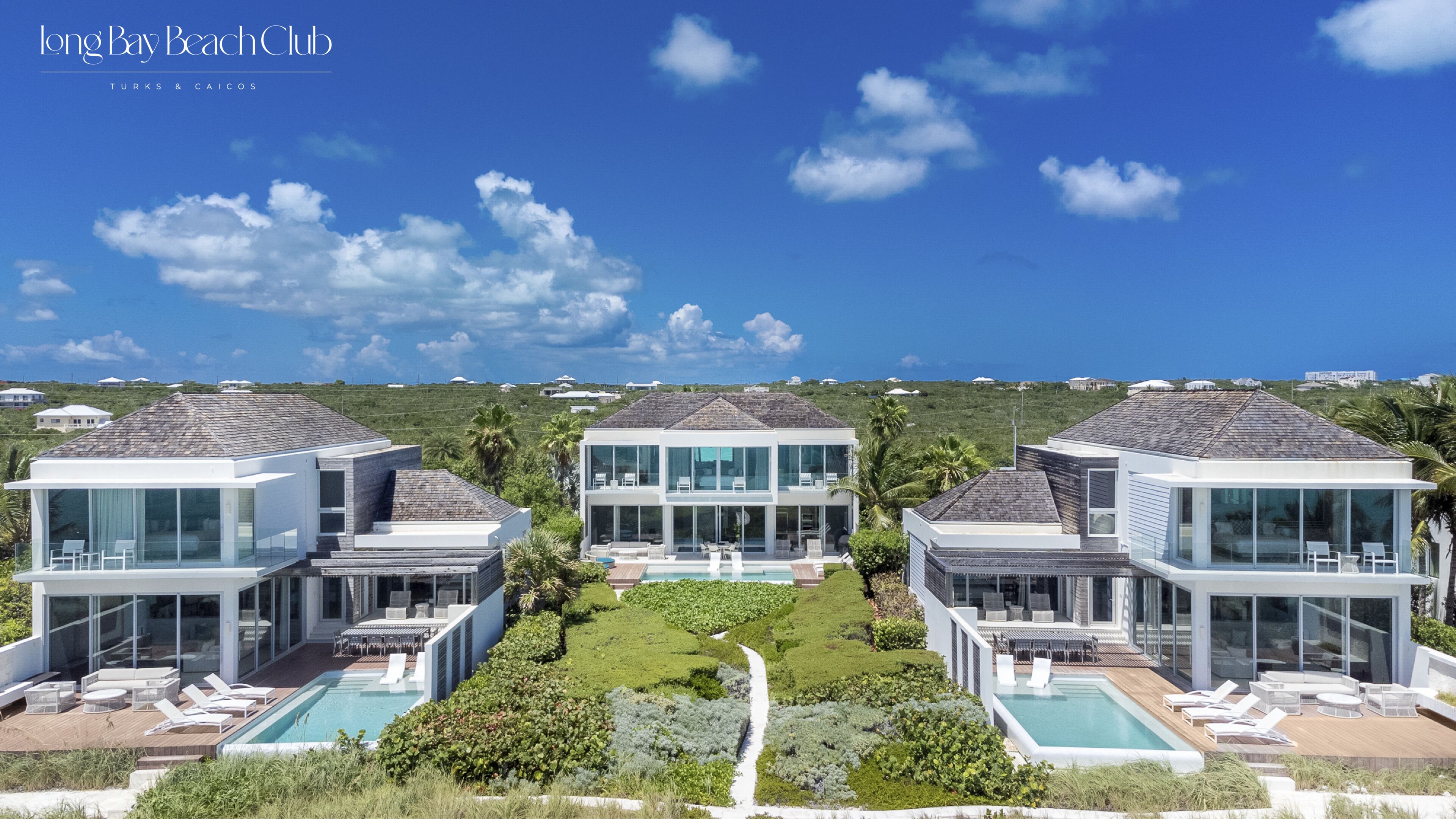 A modern resort with three connected villas featuring large glass windows, outdoor pools, and a lush garden.