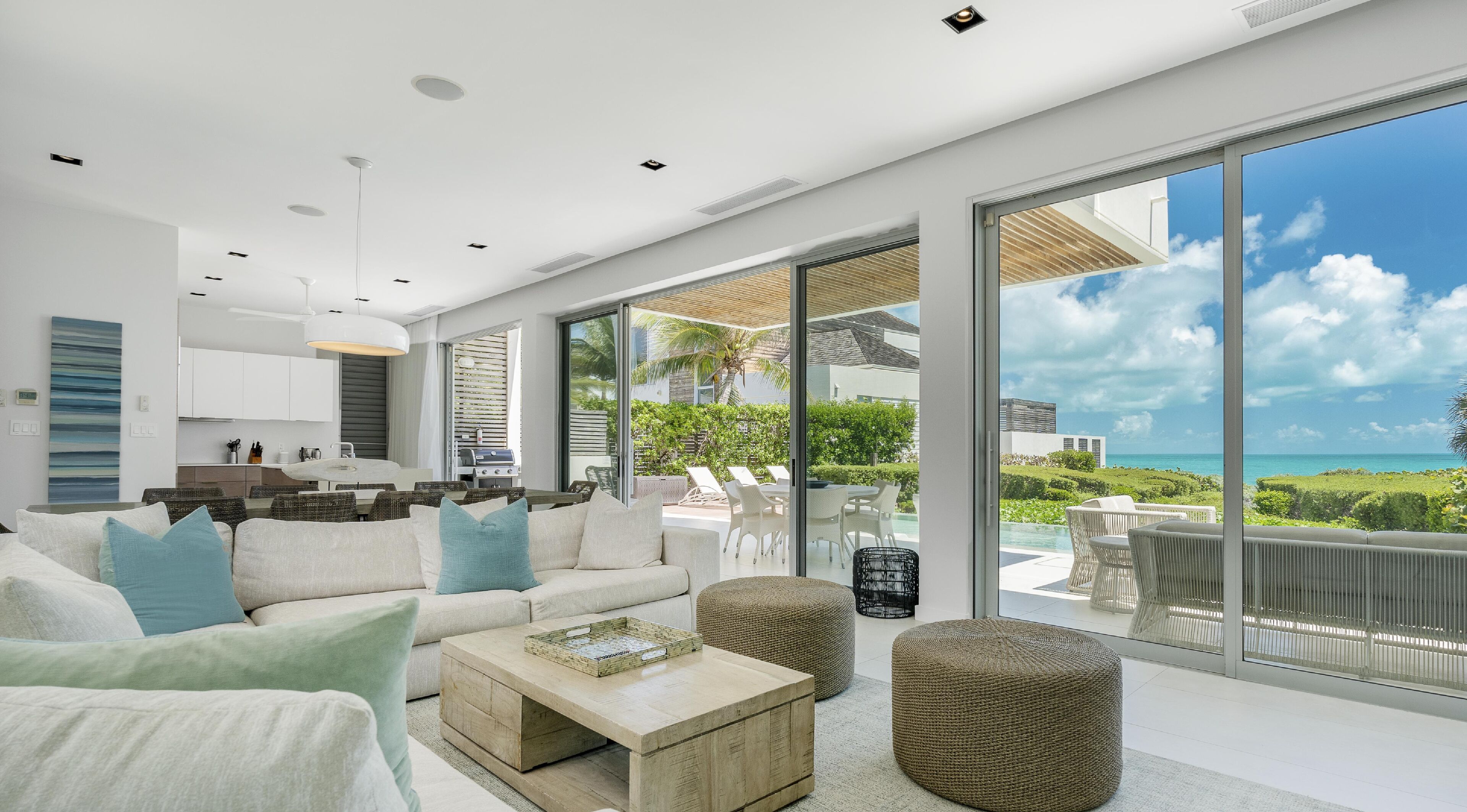 A modern living room with a large sliding glass door leading to a balcony with a view of the ocean.