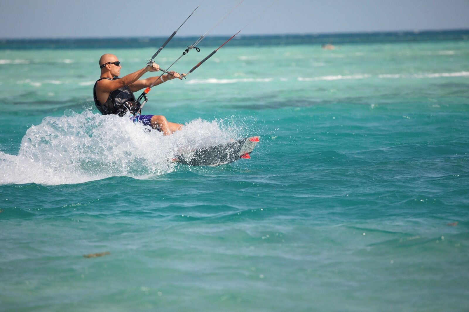 A person kiteboarding on turquoise waters.