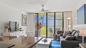 Une chambre d’hôtel moderne dotée d’un coin cuisine, d’un salon avec un canapé et une table basse, d’un ventilateur de plafond et offrant une vue sur l’extérieur.