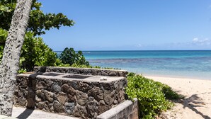 Un banc en pierre offrant une vue sur une plage et l’océan.