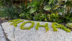Un jardin avec un sentier et une structure décorative formant le mot « TOKYO » grâce à des plantes.