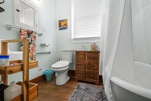 A bathroom with a wooden vanity, a toilet, a bathtub, and a shower curtain. - The O Place - Center of town and close to everything! (Galveston)