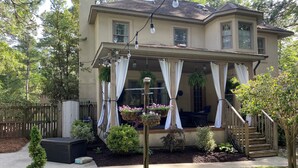 A two-story house with a covered porch, outdoor seating, and a small staircase leading to the entrance. - French Tudor in Quiet Aiken County (Aiken)