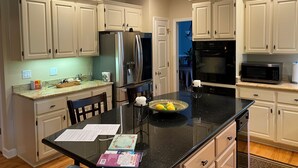 A modern kitchen with white cabinets, stainless steel appliances, and a black granite countertop. - French Tudor in Quiet Aiken County (Aiken)