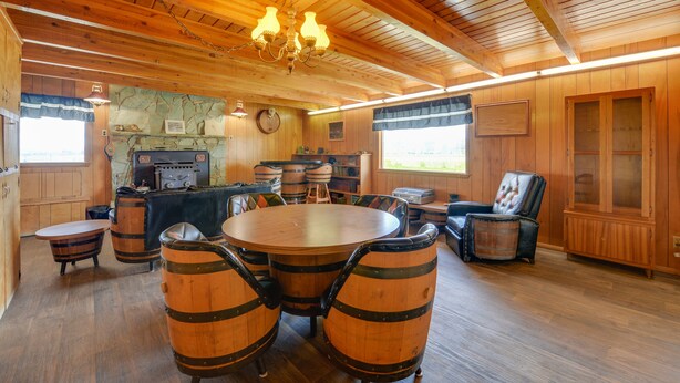 Een houten interieur met een ronde tafel en stoelen, een open haard en een kroonluchter.