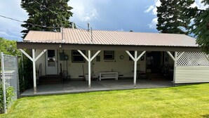 Ett enplanshus med en inglasad veranda, en ytterdörr och en liten trädgård framför huset.