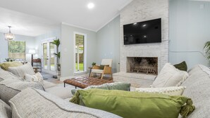 Ein Wohnzimmer mit Kamin, einer Sofagarnitur und einem an der Wand befestigten Fernseher.