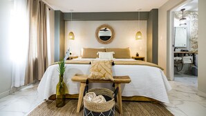 A modern bedroom with a large bed, bedside tables, a mirror, and a wooden bench. - EVA Resort (Savaneta)