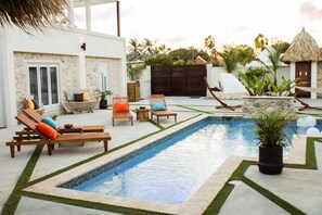 A pool area with lounge chairs and a small garden.