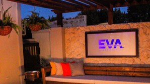 An outdoor seating area with a stone wall, a framed sign reading "EVA", and a lit display case. - EVA Resort (Savaneta)