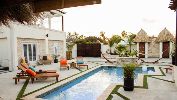 A pool area with lounge chairs and a small garden. - EVA Resort (Savaneta)