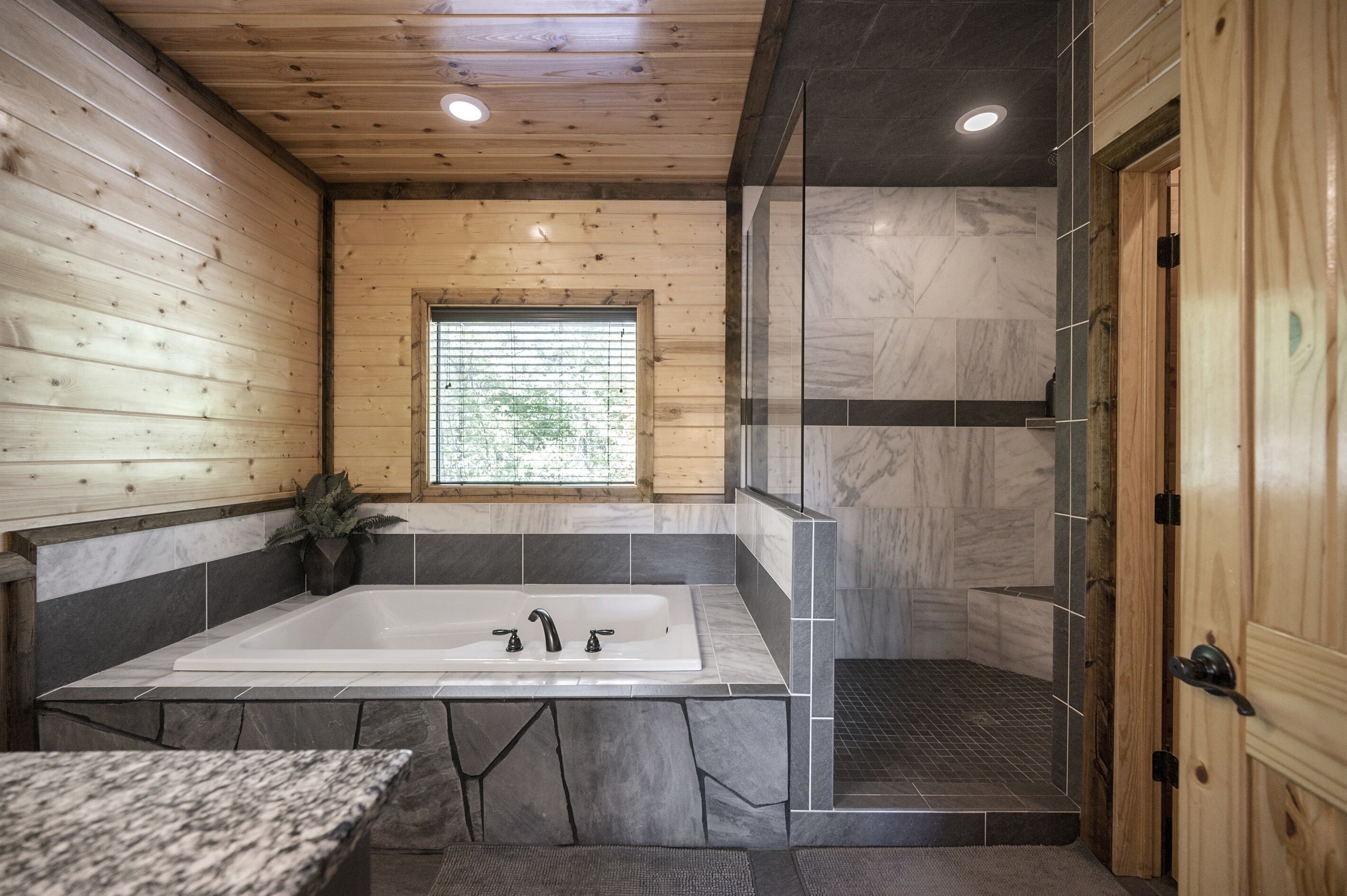 Une salle de bain moderne dotée d’une grande baignoire, d’un espace douche et d’un plafond en bois.