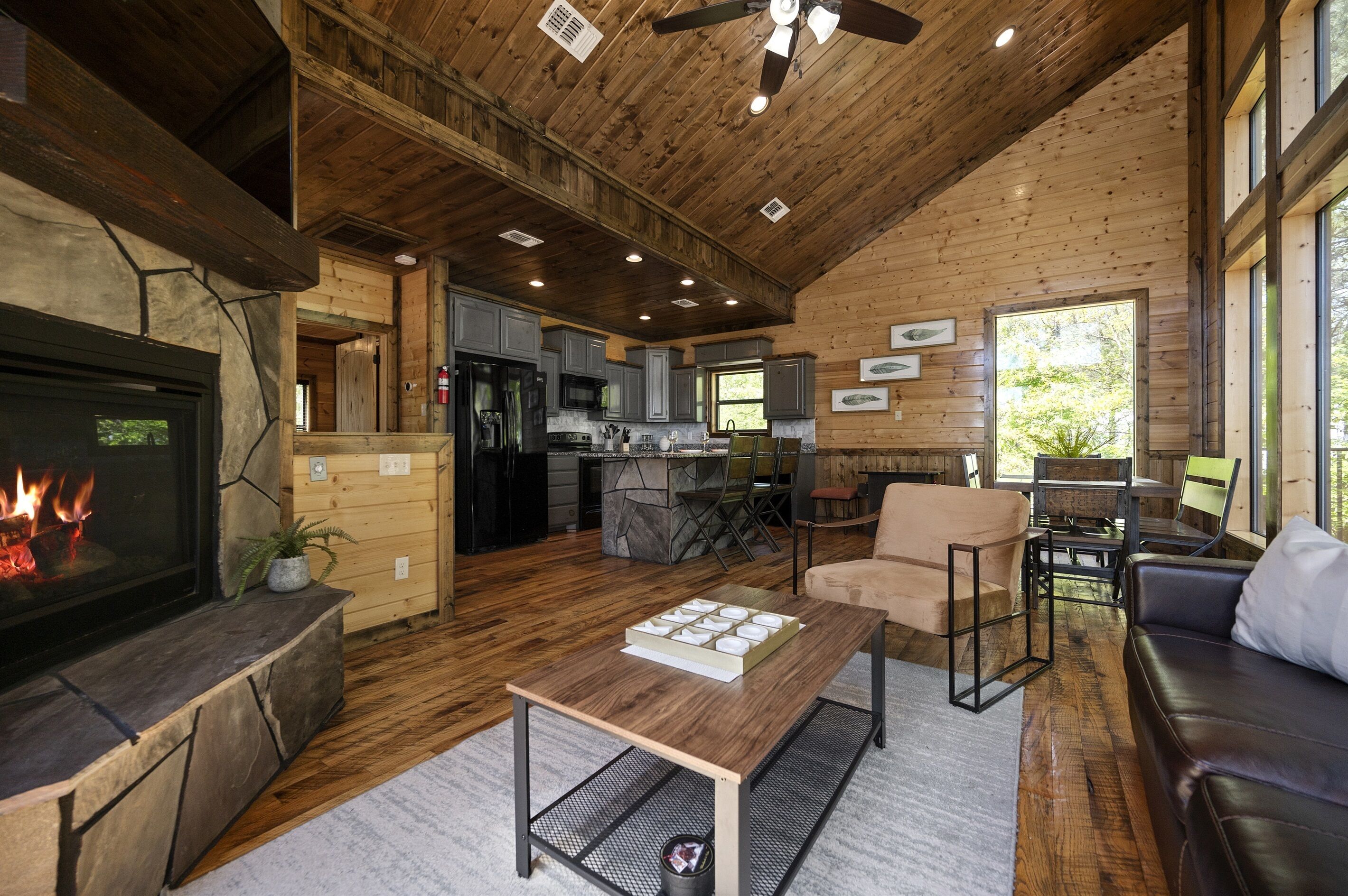 Interior acogedor de una cabaña con chimenea, pisos de madera, comedor y cocina.
