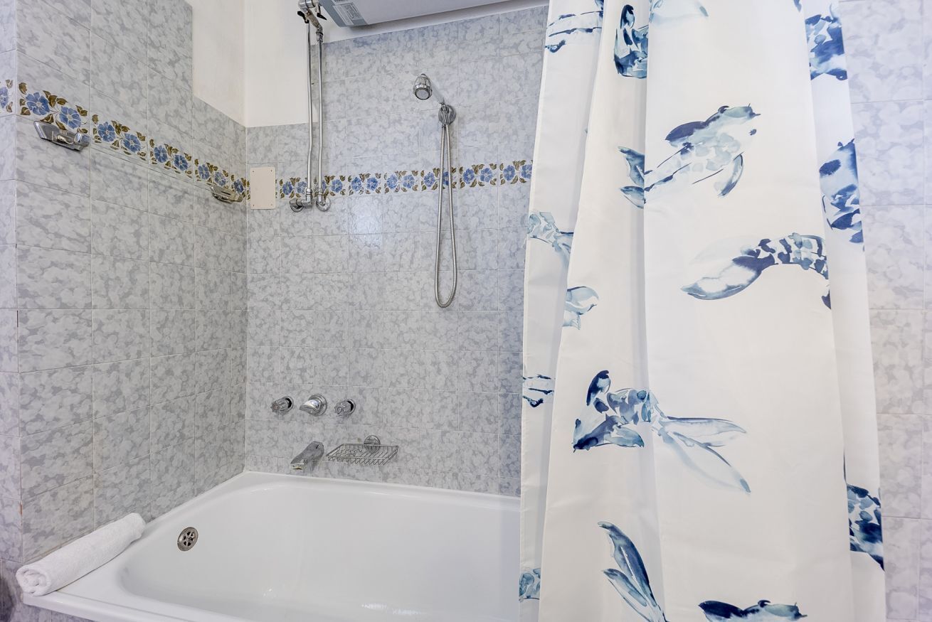 Une salle de bain avec une baignoire, une douche et un rideau à motifs floraux.