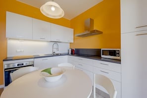 A modern kitchen with white cabinets, a microwave, and a round dining table.