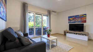 Un salon moderne avec un canapé, une table basse, un téléviseur et un tableau accroché au mur.
