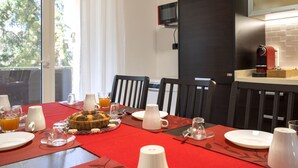 Un coin repas avec une table mise pour le petit-déjeuner, un téléviseur fixé au mur et une machine à café.