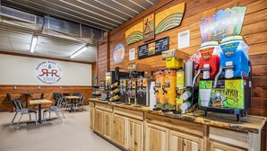 A café with a wooden interior, a counter with various coffee machines, and a sign indicating it is Roaring River Hills Campground & Cabins.