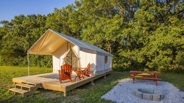 A small cabin with a deck, outdoor seating, and a fire pit.