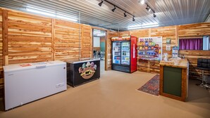 A room with wooden walls, a refrigerator, a vending machine, and a counter with a logo.