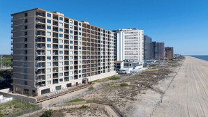 A beachfront hotel with multiple floors, balconies, and a beach access walkway. - Oceanfront Condo with Dual Views (Ocean City)