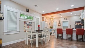 A dining area with a wooden floor, white chairs, and a table. There are red chairs at the end of the table. - Native Inspired, Peaceful, & Practical Home. (Oklahoma City)