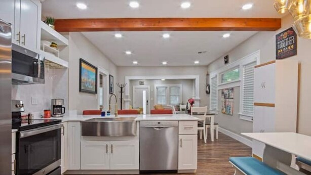 A modern kitchen with white cabinets, stainless steel appliances, and a central island. - Native Inspired, Peaceful, & Practical Home. (Oklahoma City)