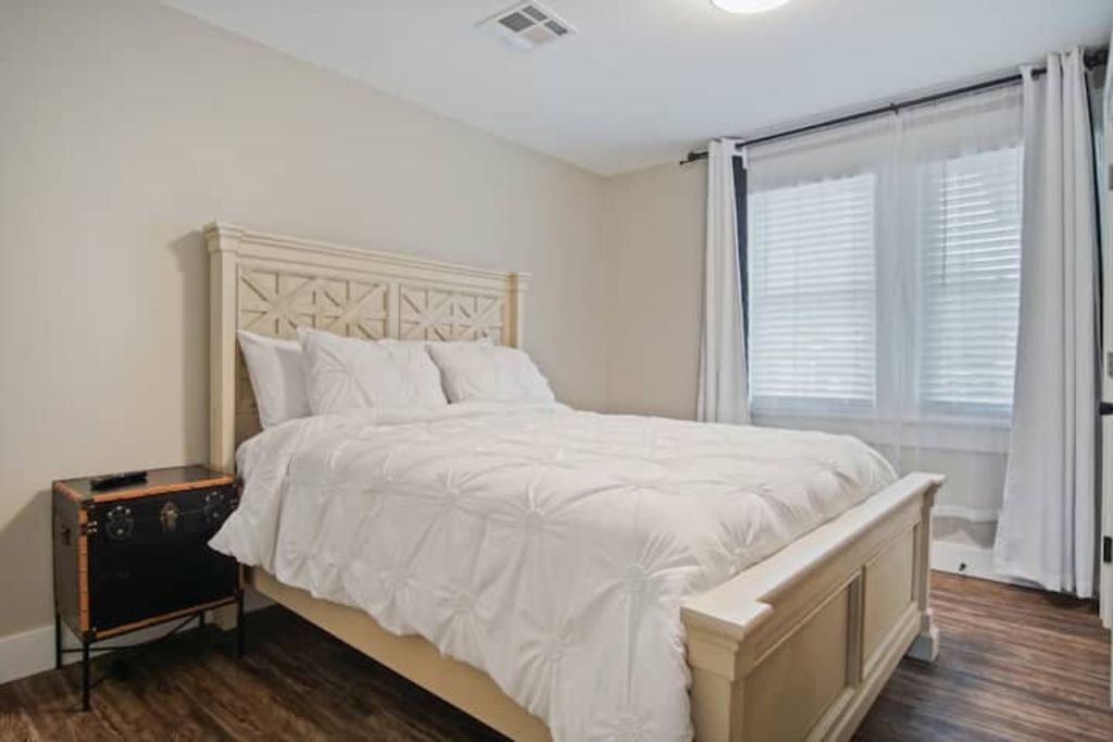 A bedroom with a bed, a nightstand, and a window with curtains.