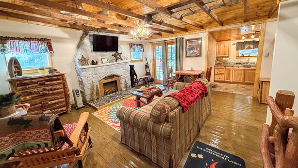 A rustic cabin interior with a stone fireplace, wooden furniture, and a cozy seating area.