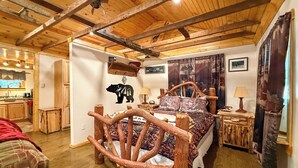 A cabin-style room with a rustic wooden bed, a bear wall decal, and a mountain-themed curtain.