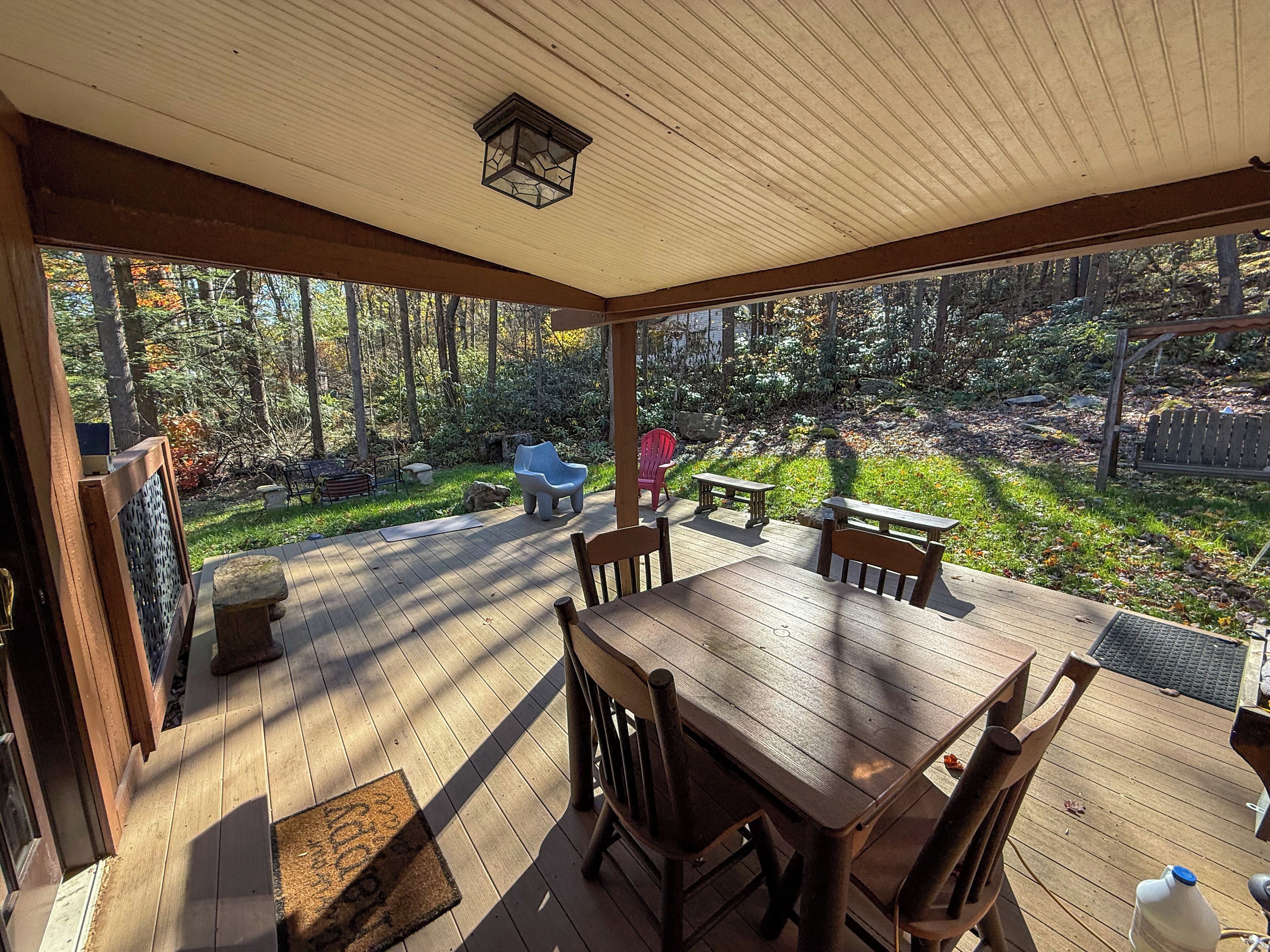 A wooden deck with a table and chairs, overlooking a forested area.