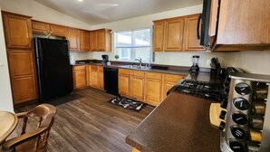 Una cocina moderna con armarios de madera, un refrigerador negro, una estufa a gas y un horno empotrado.