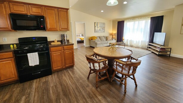 Una cocina moderna con armarios de madera, una estufa negra y un comedor con una mesa y sillas de madera redonda.