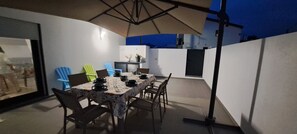 Enjoy dining al fresco in this outdoor space with a table set for four, shaded by a large umbrella.