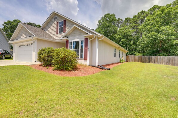 A single-story house with a garage, a small front yard with a bush, and a wooden fence in the background. - Swansboro Vacation Rental, 4 Mi to Hammocks Beach! (Swansboro)