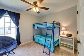 A bedroom with bunk beds, a ceiling fan, a window with curtains, a chair, and a bedside lamp. - Swansboro Vacation Rental, 4 Mi to Hammocks Beach! (Swansboro)
