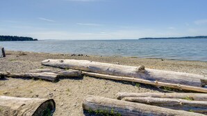Ein Strand mit Treibholz und ruhiger See.