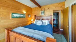 Ein Schlafzimmer einer Holzhütte mit einem großen Bett, Holzwänden und einem gerahmten Bild an der Wand.