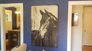 A room with a blue wall, a wooden floor, a sofa, and a large abstract artwork.